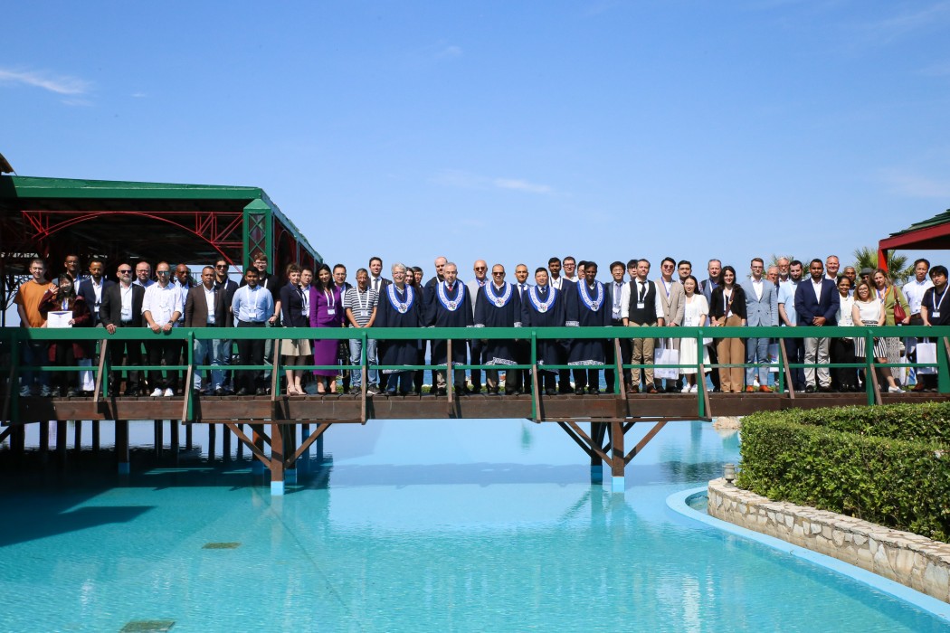 En gruppe mennesker er samlet på en gangbro over et basseng. 