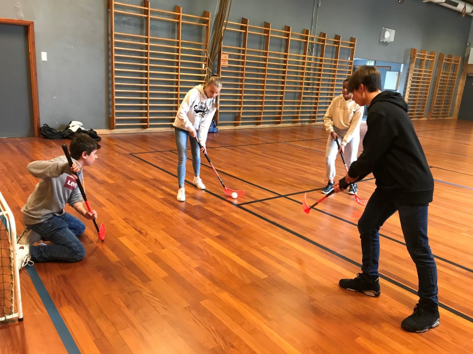 Tre gutter og en jente som spiller innebandy