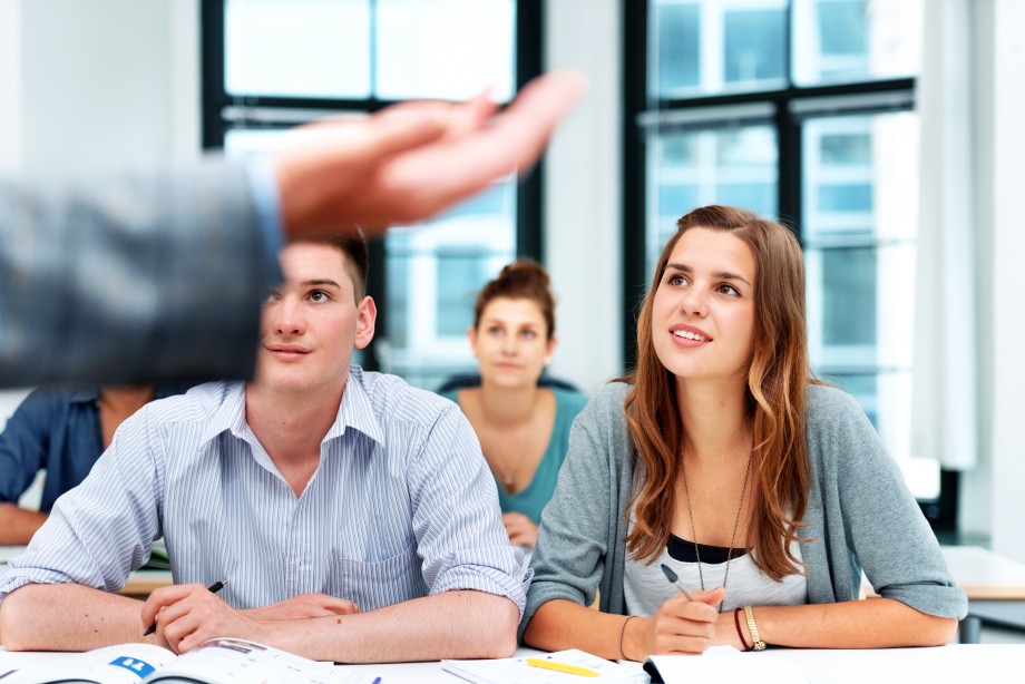 Voksne som står rundt et bord og diskuterer. Voksne på kurs.