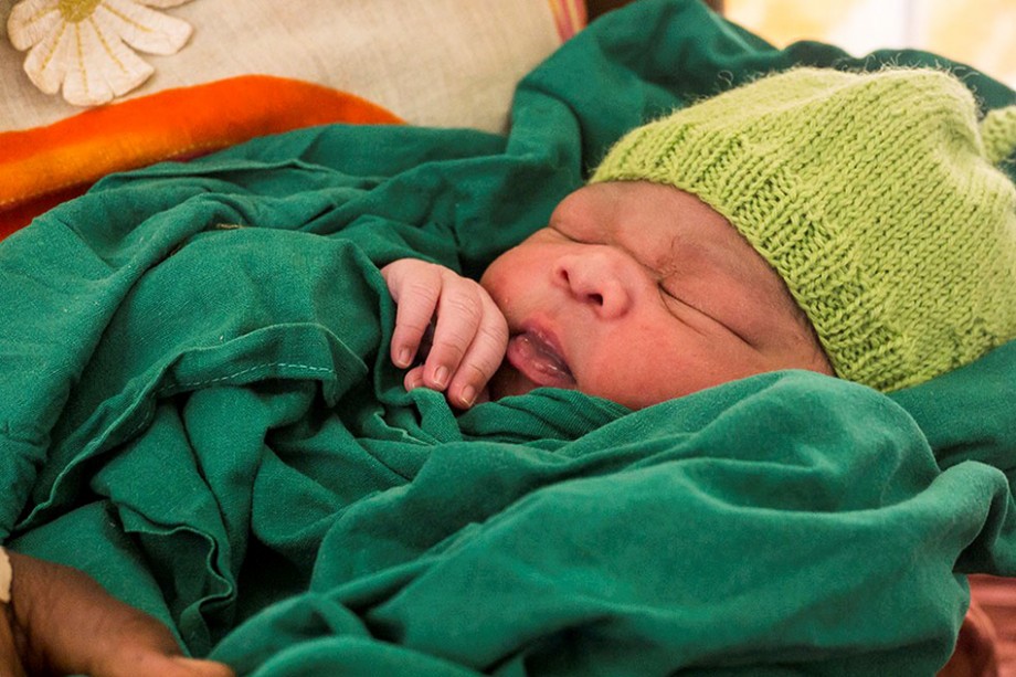 Nyfødt baby innpakket i grønt tøy