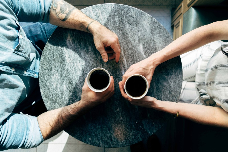 To mennesker sitter ovenfor hverandre med hver sin kaffekopp på et bord