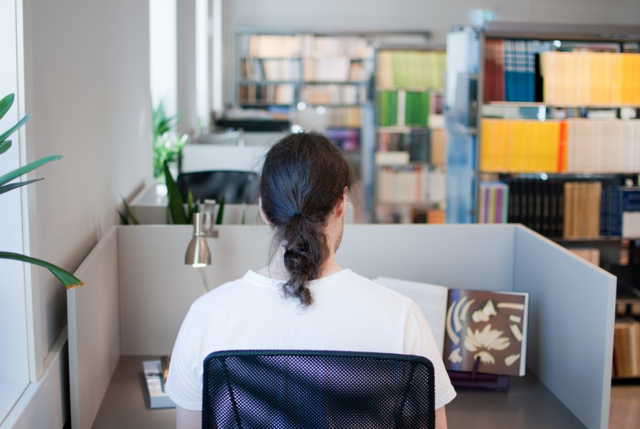 Person sitter ved leseplass i biblioteket og studerer