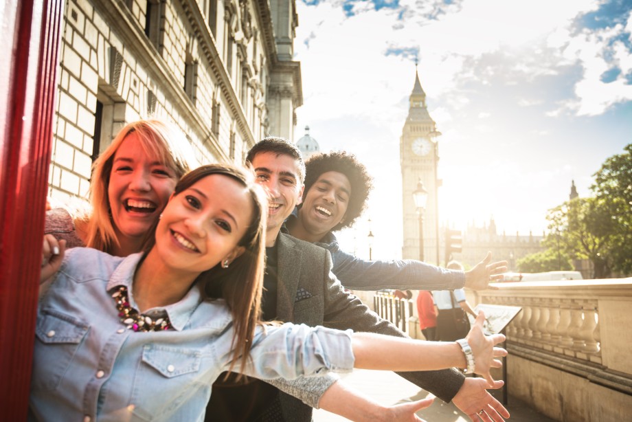 Fire unge mennesker som står sammen og smiler foran Big Ben i London