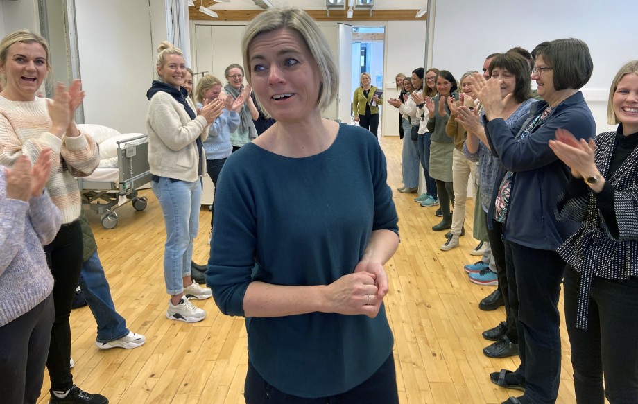 Kvinnelig prisvinner foran jublende forsamling.
