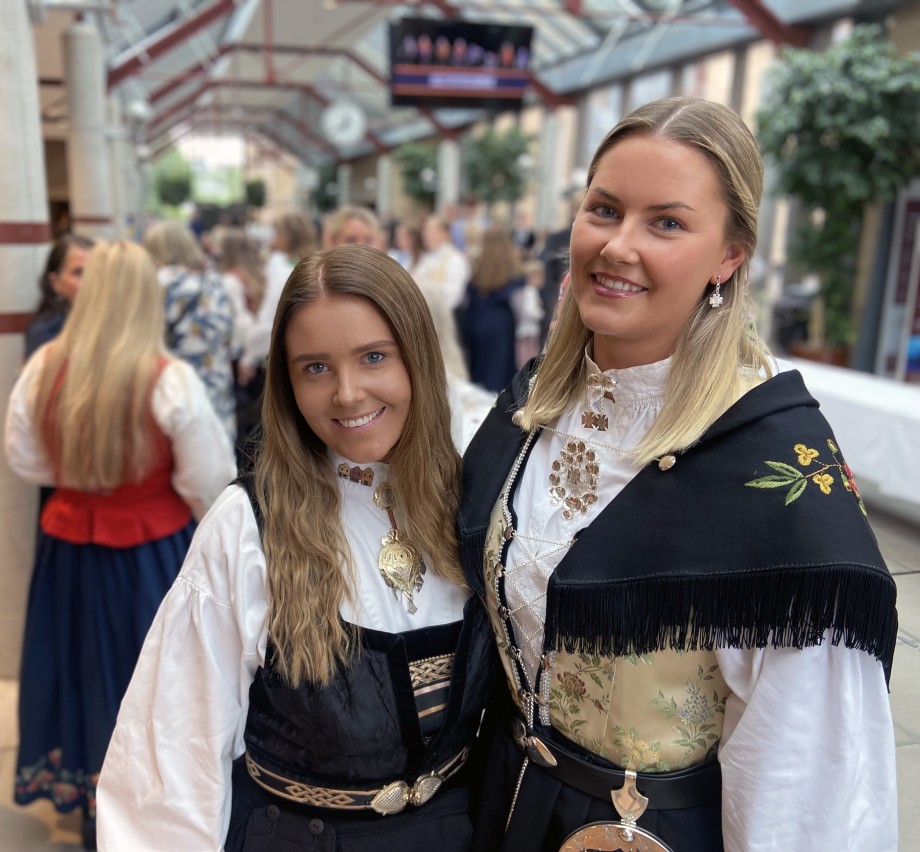 Kvinnelige studenter i bunad i en foajé