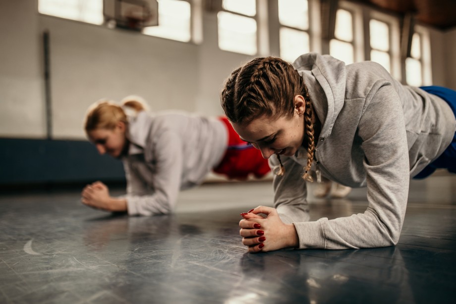 To jenter trener styrketrening i gymsal