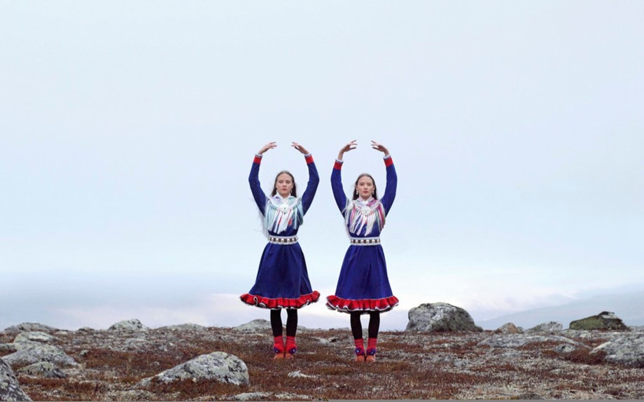 Still from the Sámi film 'Birds in the Earth' showing two dancers in Sámi dress poised to begin dancing (Helander, 2019)