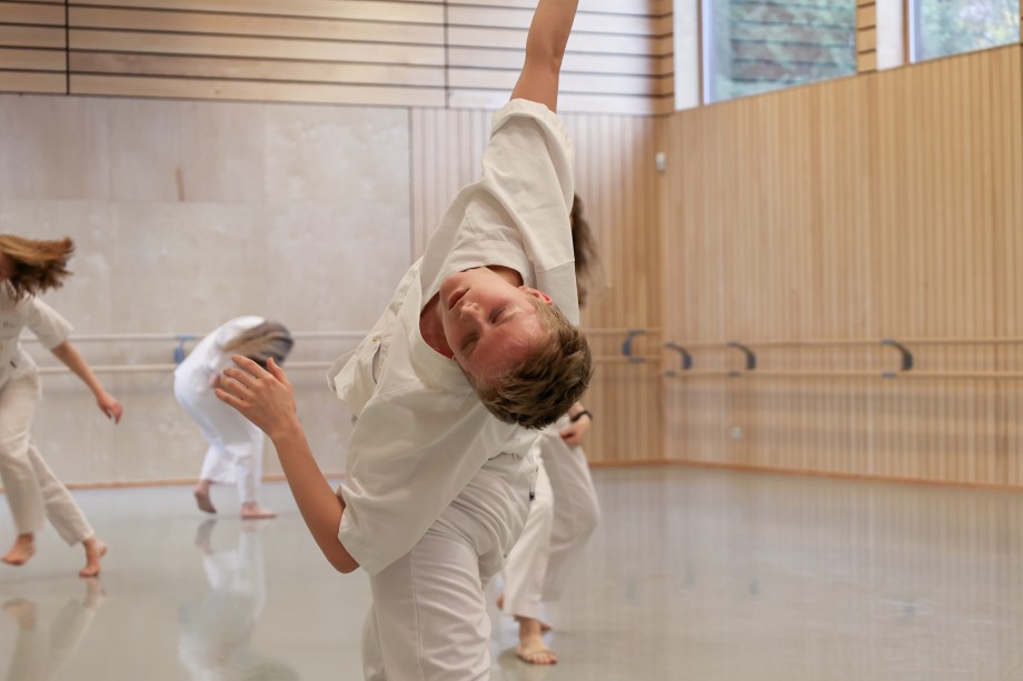 Danser i bevegelse, kledd i hvitt fra topp til tå. Foto.