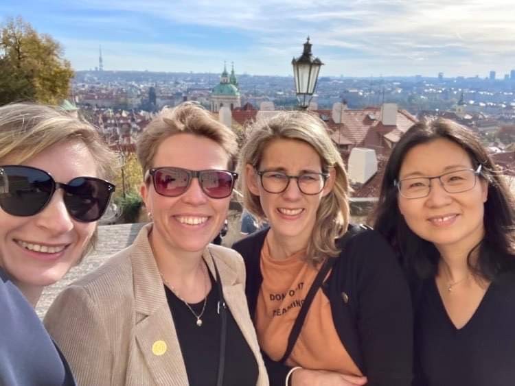 Fire kvinner på en solskinnsdag foran utsikten til en storby.
