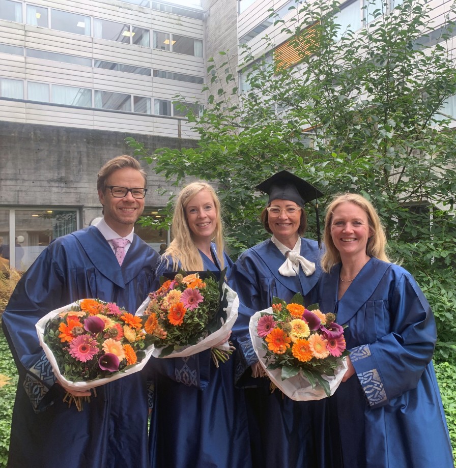 Fire forskere med kapper og blomster.