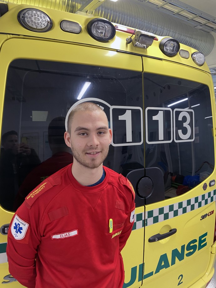 Mannlig student i uniform foran ambulanse.