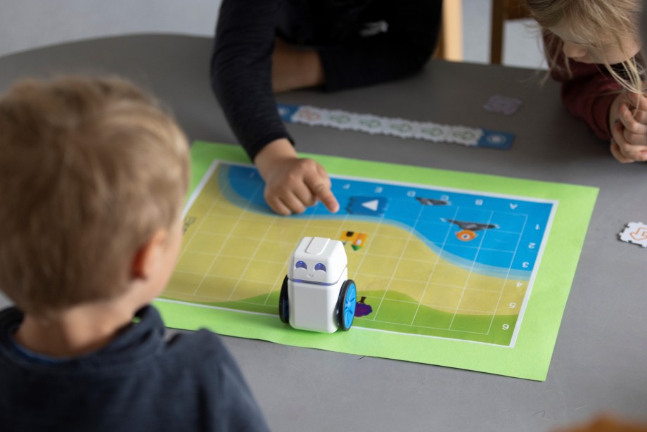 Et bilde med tre barn som koder roboten KUBO til å finne en skatt.