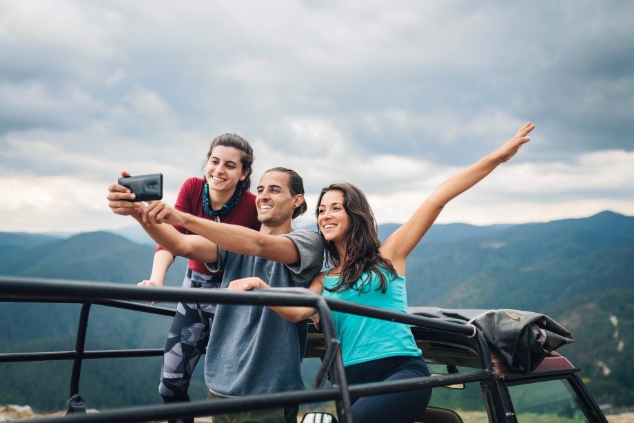 to unge menn og en kvinne tar en selfie sammen ute i naturen