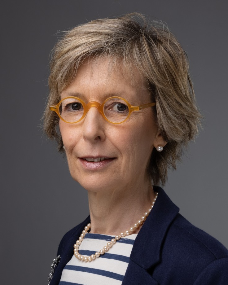 Smiling woman with glasses and necklace.