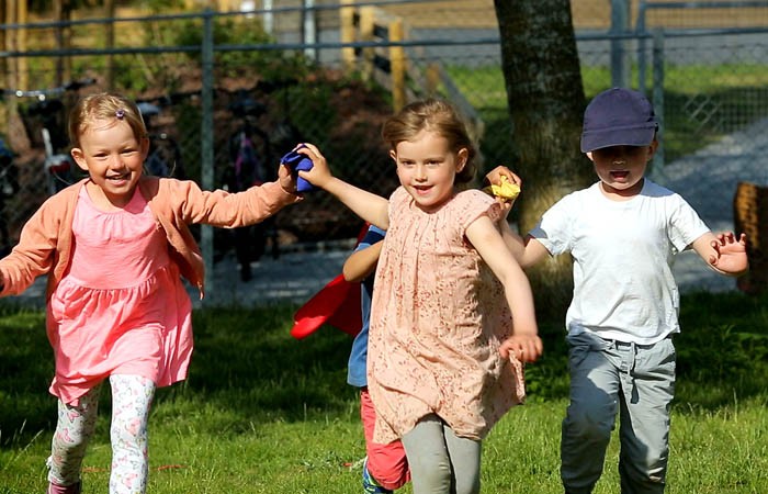 Foto av tre barn som løper. To av barna samarbeider om å holde en ertepose.