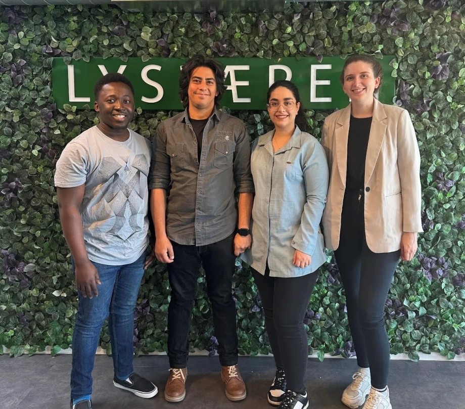 Four people standing in front of a sign with "Lyspæren".