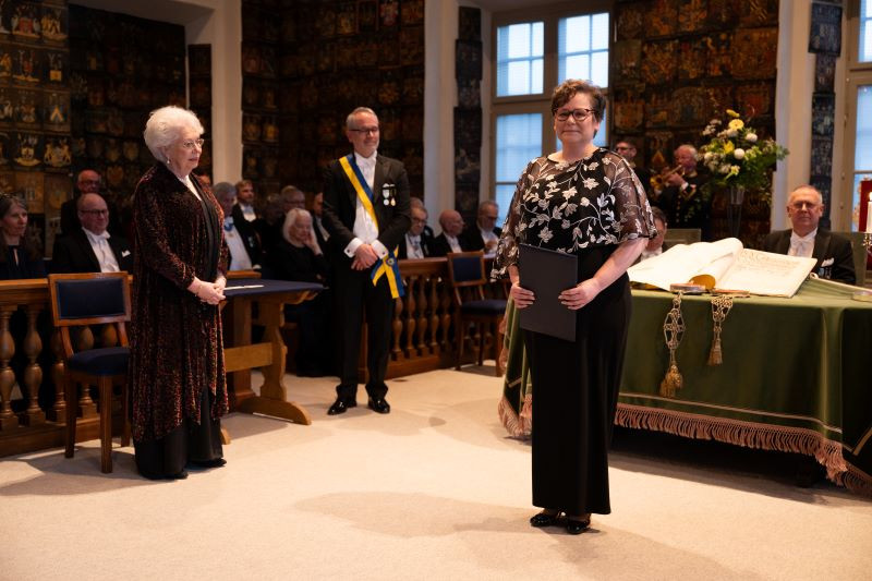 Kvinne med diplom med pent kledde folk rundt seg