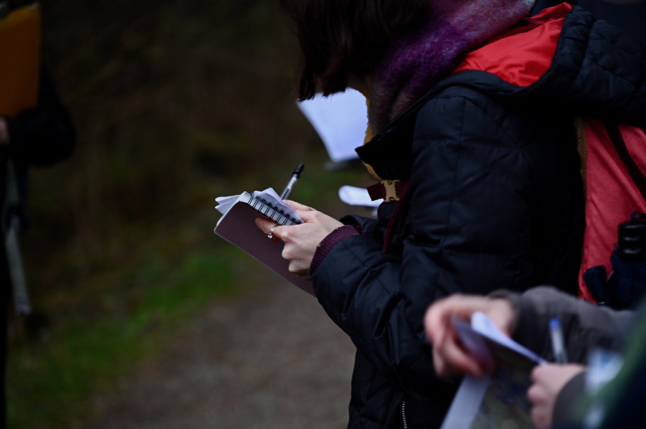 People standing among trees writing in notebooks