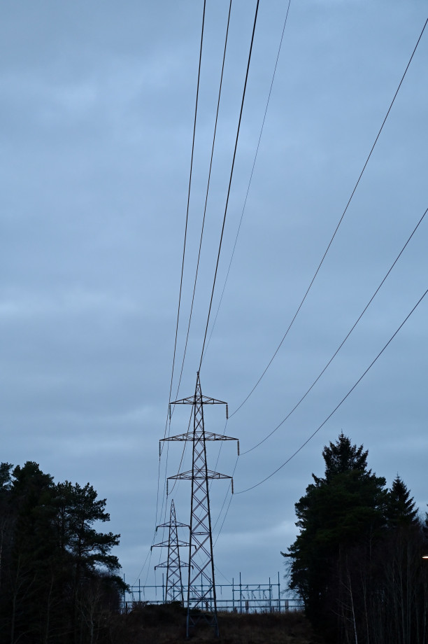 Power lines run from top right to bottom centre with pylons in the centre of the picture. Trees stand to either side framing the pylons