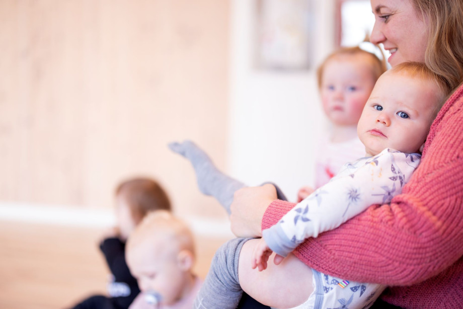 En kvinne holder en baby som ser inn i kamera