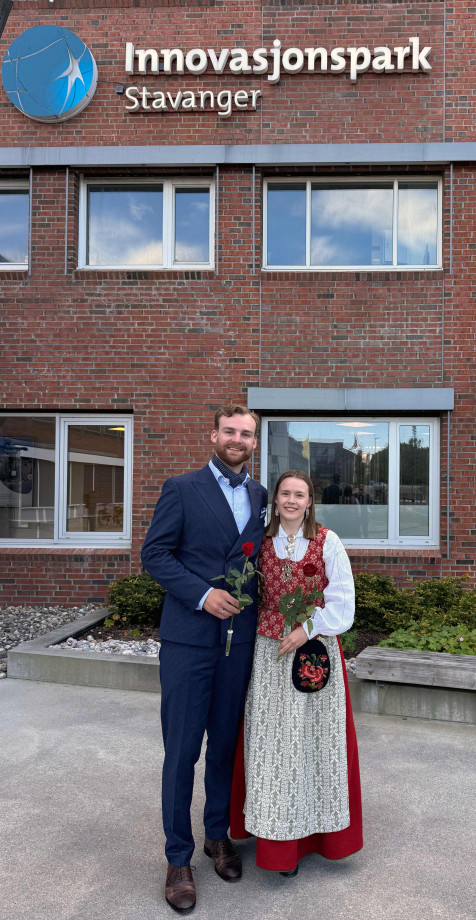 To smilende studenter i finklær
