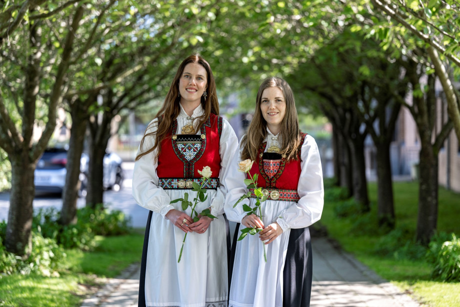 To smilende studenter i finklær