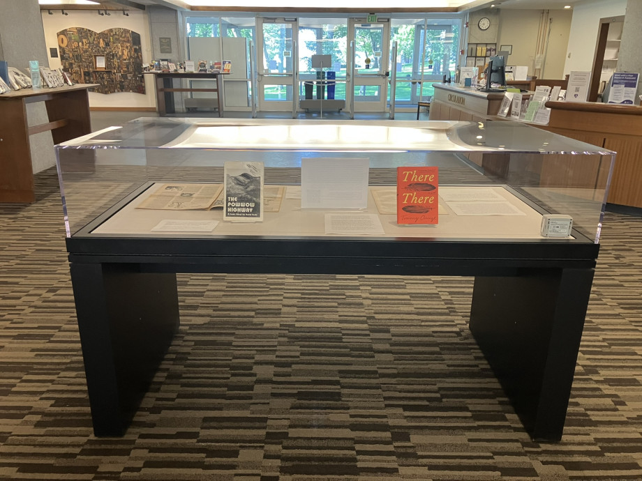 Books are on display in a glass display case that is centrally positioned in the entrance to a library
