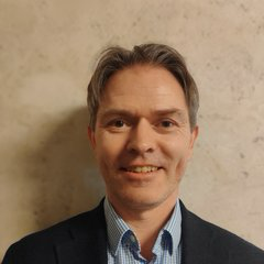 Mann i dress inntil en vegg