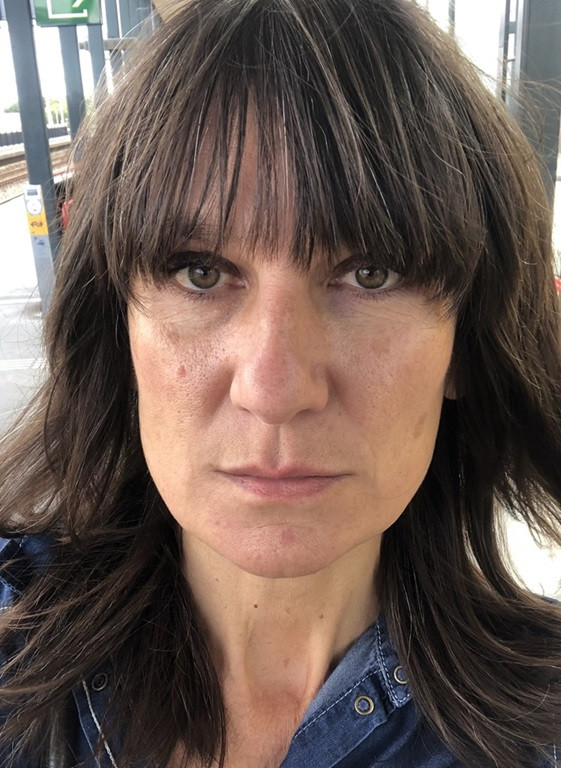 Headshot of a dark-haired woman staring seriously towards the camera