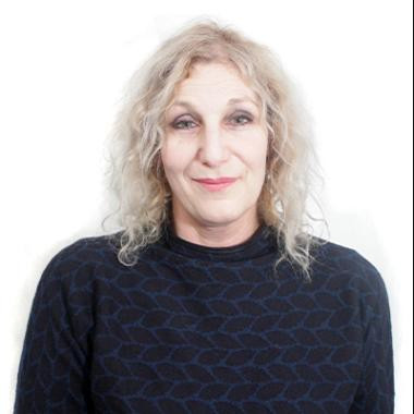 A woman in a black top looks towards the camera