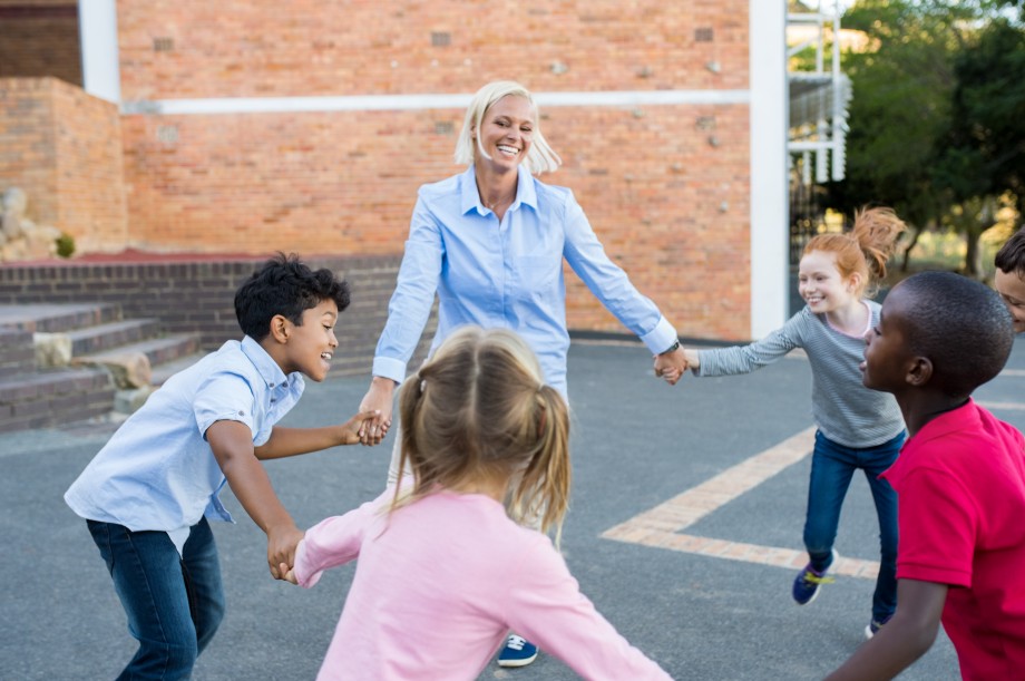 Voksen leker ringlek utendørs med barn på SFO