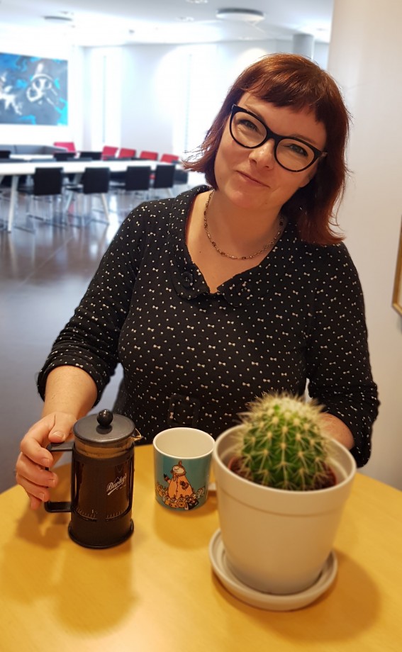 Ingrid Rusnes sitter og drikker kaffe ved et bord.