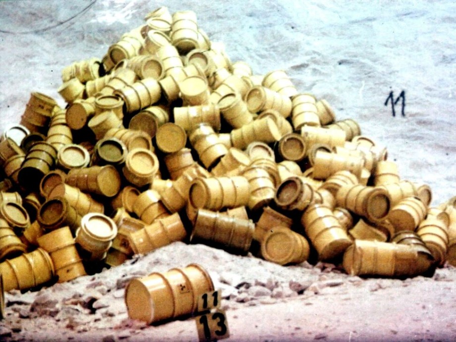 Yellow nuclear waste barrels lie in a pile at a storage facility