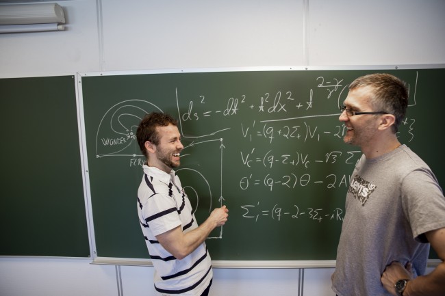Sigbjørn Hervik (veileder) og Ben David Normann løser universets gåter med formler på grønn tavle