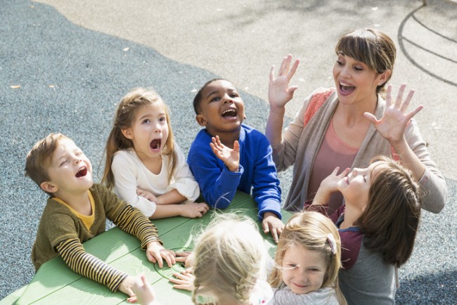 Kvinnelig barnehagelærer er utendørs sammen med en gruppe barn
