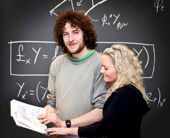 Kvinne og mann står sammen foran en tavle med matematikk på.