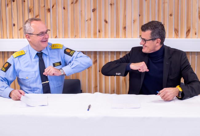 Tolldirektør Øystein Børmer og rektor Klaus Mohn gir hverandre albuen etter å ha signert samarbeidsavtale