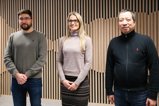 Professorene Krisztian Balog, Kjersti Engan og Chunming Rong står foran en palisadevegg