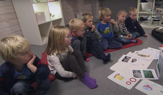 Syv barn høre på når barnehagelærer forteller.