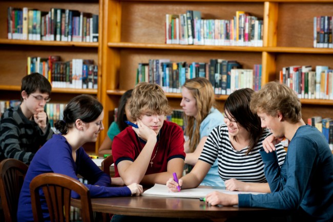 tenåringer leser sammen i bibliotek