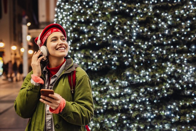 kvinne med hodetelefoner ved juletre ute