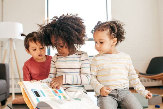 Tre små barn leser sammen i en bildebok