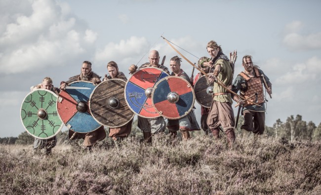 En gruppe mennesker har kledd seg ut i klær fra vikingtiden og gjør seg klar til kamp