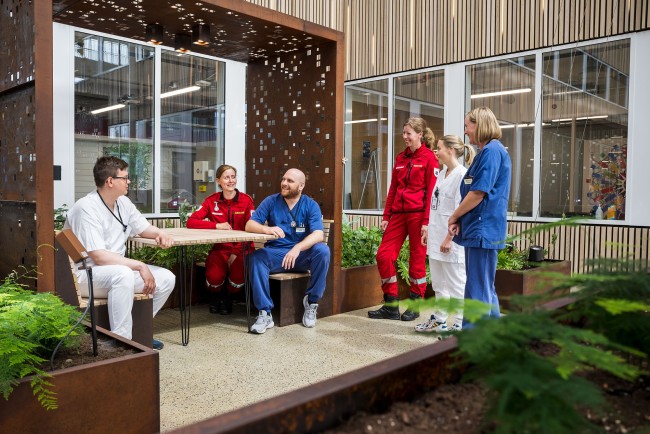 Helsepersonell i hvite, blå og rød uniformer snakker sammen