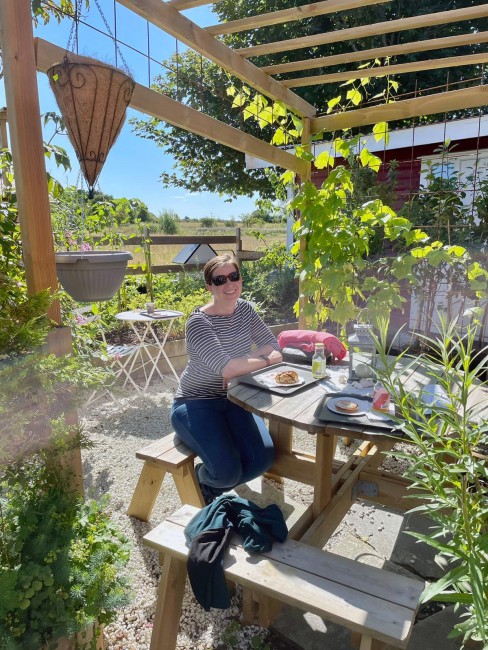 Kvinne som sitter på en benk i landlige omgivelser.