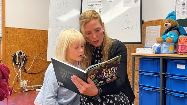 Jente og lærer leser sammen i klasserommet