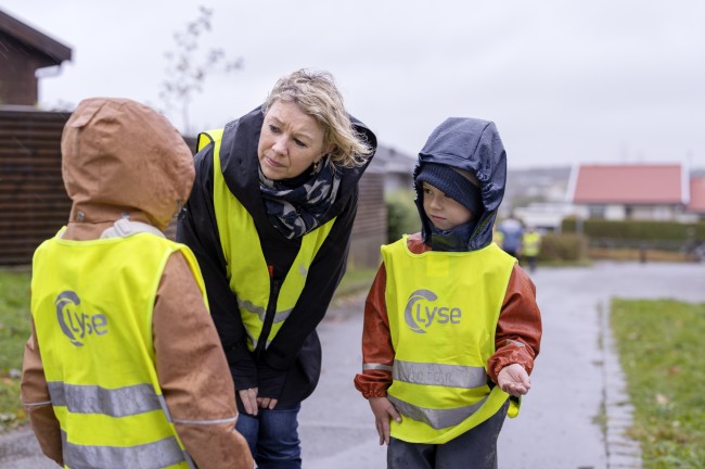 En lærer snakker med to elever i en skolegård på en regnværsdag.