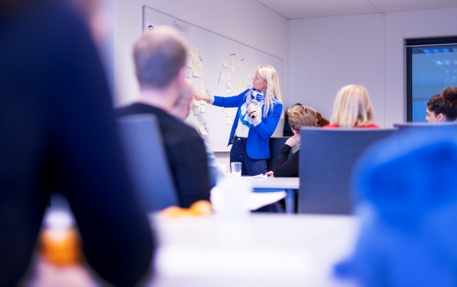 Klasserom med foreleser som peker på whiteboard