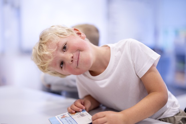 En gutt sitter ved et bord og smiler til kamera. Foto: Elisabeth Tønnessen/Læringsmiljøsenteret, UiS