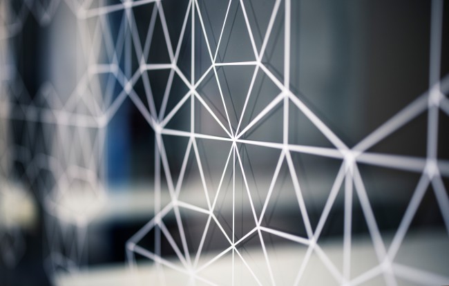 Hvite linjer som danner geometriske figurer på glassplate med gjenskinn